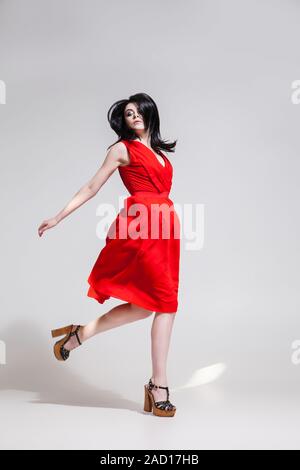 Black-haired woman twisting in red dress Stock Photo