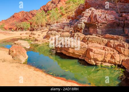 Aerial view of rugged rocky cliffs of Ormiston Gorge in West MacDonnell Range National Park reflected in a pool on the river in dry season. Northern Stock Photo