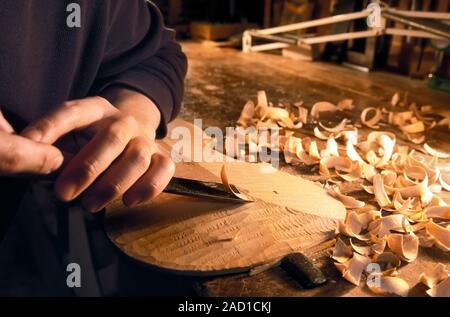 Violin-making workshop. Close-up of a chisel being used to gouge the back of a violin down to size. The back of a violin is made from maple wood, in e Stock Photo