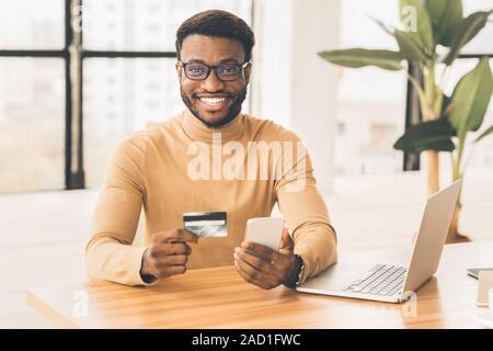 African american man holding credit card and smartphone Stock Photo