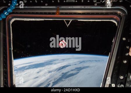Chance in space. Gaming die (red) floating in front of one of the windows in the cupola of the International Space Station in Earth orbit. Photographe Stock Photo
