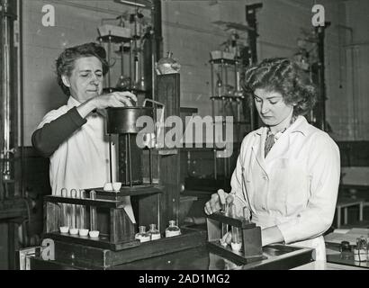 Mining safety lamp inspection. Laboratory workers handling and inspecting a mining safety lamp. Such lamps were designed to provide illumination in a Stock Photo