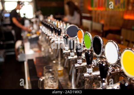 Lot of vintage Golden beer taps in the bar with the bartender in the background Stock Photo