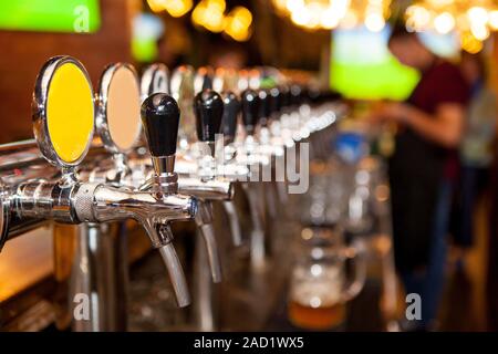 Lot of vintage Golden beer taps in the bar with the bartender in the background Stock Photo