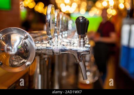 Lot of vintage Golden beer taps in the bar with the bartender in the background Stock Photo