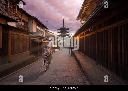 Kyoto, Japan - November 4 2018: A woman dressed like a Maiko taking a photo of Yasaka Pagoda with sun rays at sunrise in Gion, Kyoto Stock Photo