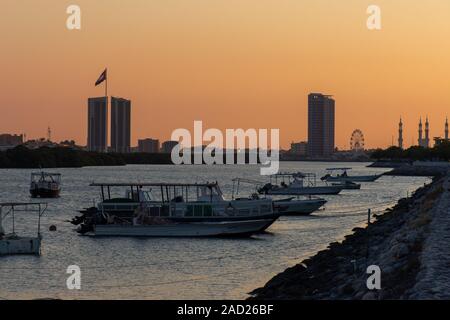 Panorama of a Ras al Khaimah View to the flag pole and mosque as the sun sets in flowing yellow and orange. Stock Photo