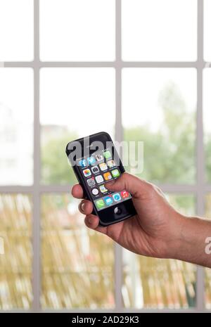 Smartphone use. Hand holding a smartphone displaying start-up icons for several mobile apps. Mobile apps are computer programs that are designed to ru Stock Photo