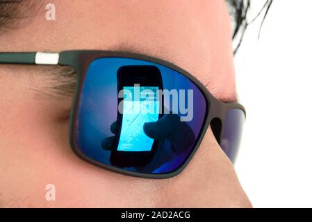 Smartphone use. Reflection in mirrored sunglasses showing a hand holding a smartphone displaying a mapping mobile apps. Mobile apps are computer progr Stock Photo