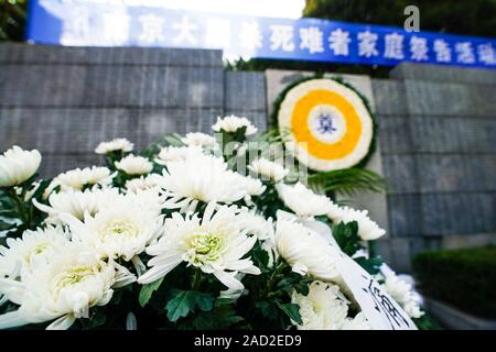 Nanjing, China. 03rd Dec, 2019. Photo taken on Dec. 3, 2019 shows flowers laid before the memorial hall wall where the victims' names are engraved during a commemoration activity in Nanjing, capital of east China's Jiangsu Province. Starting Tuesday, family members of the victims of the massacre began a series of commemoration activities such as laying flowers and burning incense before the memorial wall where the victims' names are engraved. The Nanjing Massacre took place when Japanese troops captured the city, then China's capital, on Dec. 13, 1937. Credit: Xinhua/Alamy Live News Stock Photo