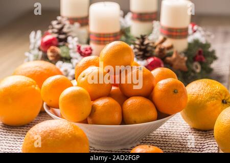 Tangerines and oranges on christmas table with advent wreath Stock Photo