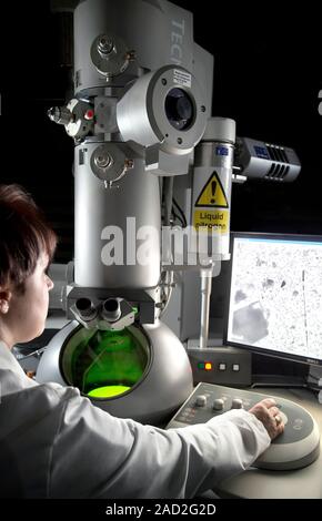 Transmission electron microscopy. Researcher operating a transmission electron microscope (TEM). In a TEM, a beam of electrons is propelled down throu Stock Photo