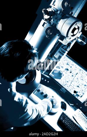 Transmission electron microscopy. Researcher operating a transmission electron microscope (TEM). In a TEM, a beam of electrons is propelled down throu Stock Photo