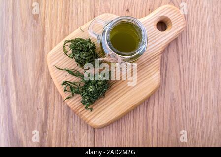 Hemp oil in a glass jar, cannabis leaves on the background of the wooden boards. Top view. Stock Photo