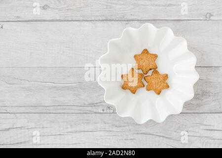 Star shaped Christmas cookies in bowl on white wood panel background with copy space. Top view. Stock Photo