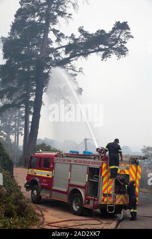 Firefighters using a fire engine hose to spray an area threatened by wildfire. Photographed in Constantia, Cape Town, South Africa, in 2015. Stock Photo