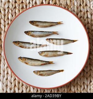 top view of smoked sprats, known as Kieler Sprotten in Germany, arranged on plate Stock Photo