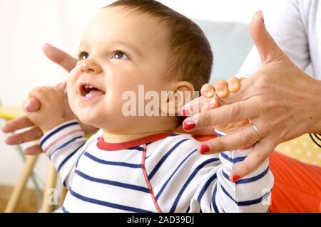 Baby boy learning to walk. 13-month-old baby boy being supported and guided by his mother as he learns to walk. Stock Photo