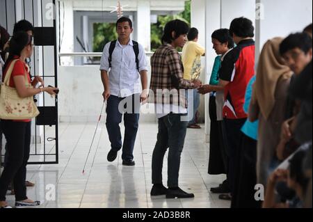 A student with a visual impairment using a white cane to navigate a corridor at university. Photographed at Makassar, Sulawesi, Indonesia. Stock Photo