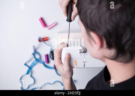 Man with screwdriver repairing sewin-machine Stock Photo