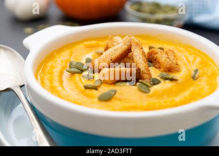Creamy carrot soup, autumn foods. Spicy, roasted vegetable soup in bowl. Dark background. Stock Photo