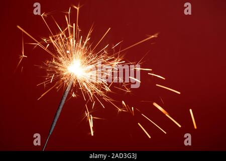 Burning sparkler on red background Stock Photo