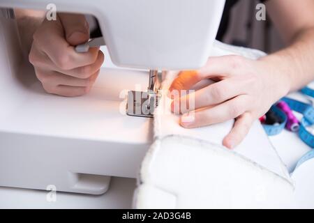 Young girl stitching white cloth Stock Photo