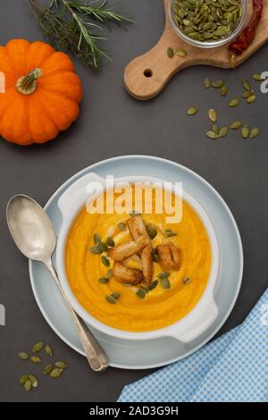 Creamy carrot soup, autumn foods. Spicy, roasted vegetable soup in bowl. Dark background. Stock Photo