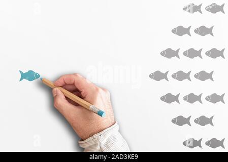 standing out from the crowd or leadership concept with group of fishes going in one direction and one going in opposite direction