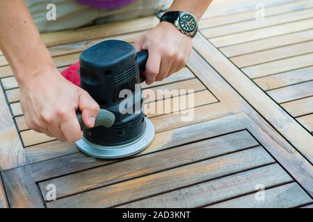 Close-up of carpenter's hands working with electric sander Stock Photo
