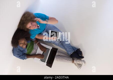 multiethnic couple sitting on the floor with a laptop and tablet top view Stock Photo