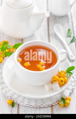 Fresh warmer herbal hawthorn tea with fresh berries in a white cup on wooden background, alternative medicine Stock Photo