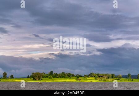 Monsoon clouds developing over a sunlit landscape and river. Photographed in India. Stock Photo