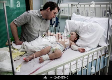 Father with baby son with pneumonia. Father comforting his 21-month-old baby son who has pneumonia and is being cared for in hospital. Pneumonia is a Stock Photo