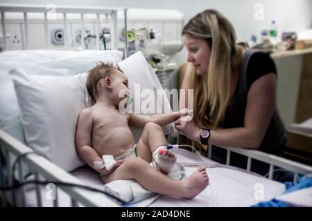 Mother with baby son with pneumonia. Mother comforting her 21-month-old baby son who has pneumonia and is being cared for in hospital. Pneumonia is a Stock Photo