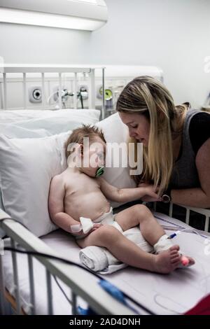 Mother with baby son with pneumonia. Mother comforting her 21-month-old baby son who has pneumonia and is being cared for in hospital. Pneumonia is a Stock Photo