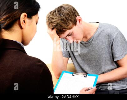Depressed young man in consultation with a doctor or psychologist. Stock Photo