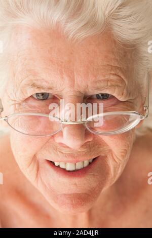 Elderly woman using reading glasses. Smiling 81-year-old woman using reading glasses. Stock Photo