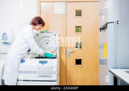 Loading centrifuge. Researcher loading samples into a centrifuge. Photographed in a biomedical research laboratory. Stock Photo
