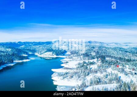 Winter in Croatia. Panorama of Lokvarsko lake and woods under snow in Gorski kotar and Risnjak mountain in background from drone. Stock Photo