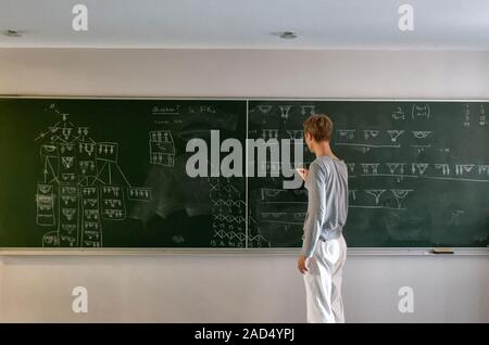 Mathematics education. A student adds to mathematical diagrams on a blackboard. Stock Photo