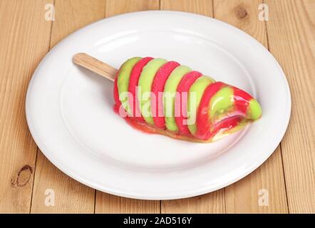 Melted colorful fruit ice cream in plate on wooden background Stock Photo