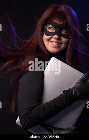 Thief in mask holds laptop Stock Photo