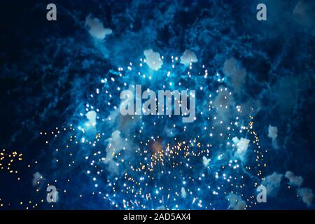Inexpensive fireworks over blue sky, red, green, blue and white with colour sparks. Selective focus. Bright and shiny. Celebration concept. Stock Photo