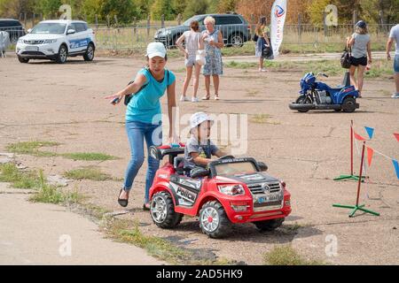 Samara, Russia - August 17, 2019: Little boy on a children's car in the Park with his mother Stock Photo