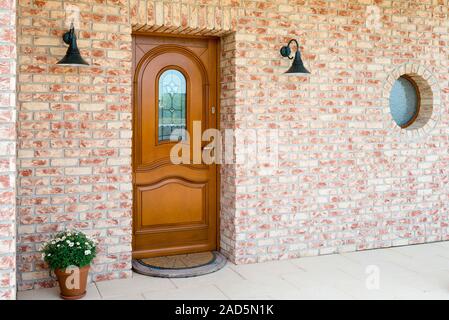 Stylish wooden front - entrance door in a detached house - embedded in a brick wall Stock Photo