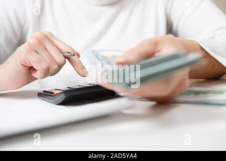 savings, finances, economy and home concept - close up of hands with calculator counting money and making notes at home Stock Photo