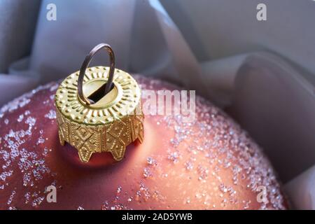 Close-up of a frosted bronze orange brown gold colored christmas ball wrapped in white paper Stock Photo