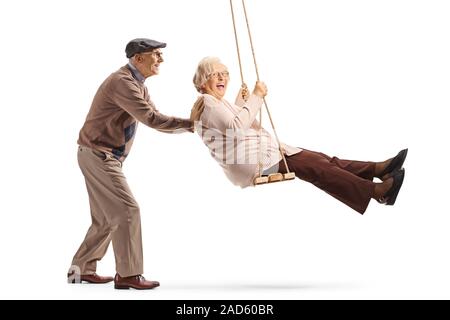 Full length shot of a senior man pushing a senior woman on a swing isolated on white background Stock Photo