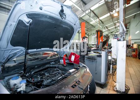 Car servicing. Technician performing a diagnostics check on a car being serviced in a service centre. Stock Photo